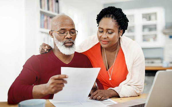 image of mature couple reviewing paperwork together at home on their kitchen table